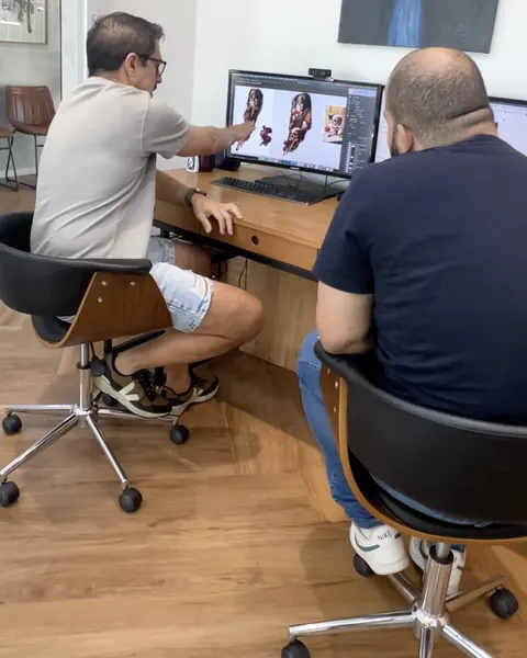 Fernando Souza na mesa de trabalho, ao lado do cliente, montando o projeto no computador.